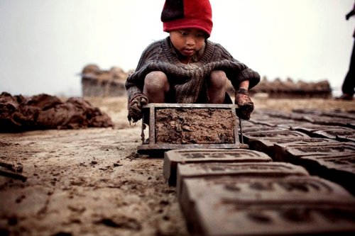 Nepal, 7 Uhr morgens. Der vier Jahre alte Yadhu konzentriert sich darauf, die Ziegelsteine in die Form zu bringen. Photographie von Luca Catalano Gonzago für CARE